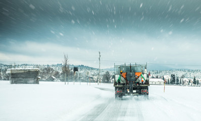 Winter service truck or gritter spreading salt on the road surface to prevent icing in stormy snow...