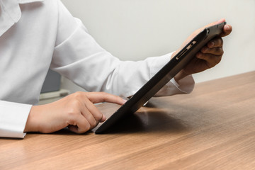 Close up hands touching screen of woman using tablet on her desk