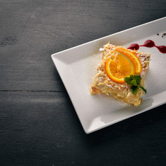 Layered cake with orange flavor. On a wooden background. Free space for your text. Top view.