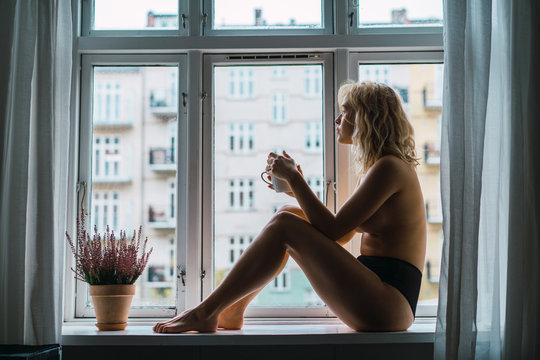 Nude model with coffee in morning