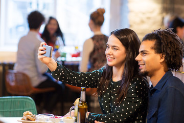 happy couple taking selfie at restaurant or bar