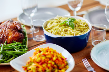 pasta with basil in bowl and other food on table