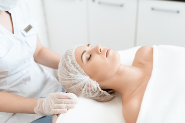 The girl came to spa salon for laser hair removal. The woman lies on the couch, the doctor prepares her for procedure.