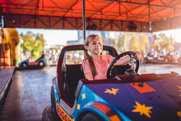 Girl driving electric cars in amusement park