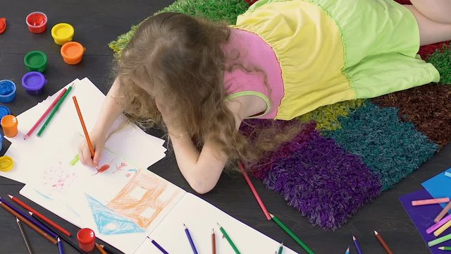 Young child lying on floor and drawing cute picture in illustration school