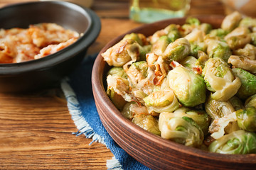 Bowl with roasted brussel sprouts with bacon on wooden table, closeup