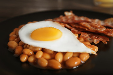 Plate with fried egg, bacon and beans, closeup
