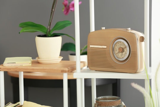 Modern radio receiver on shelf in room