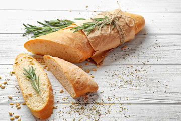 Yummy fresh bread with herbs on wooden background