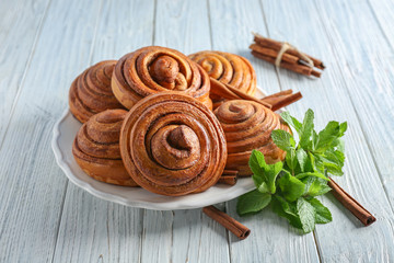 Plate with tasty cinnamon buns on table