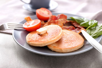Tasty breakfast with pancakes, bacon and tomato on plate