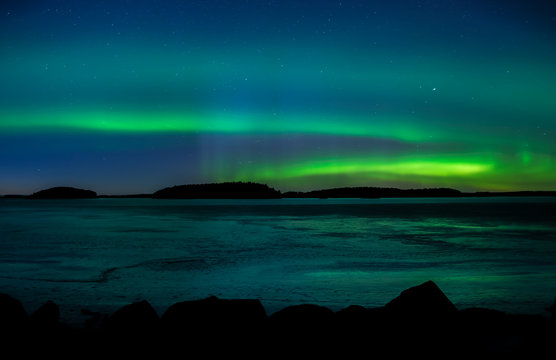 Northern lights dancing over frozen lake in Farnebofjarden national park in Sweden.
