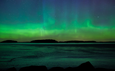 Northern lights dancing over frozen lake in Farnebofjarden national park in Sweden.