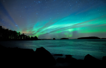 Northern lights dancing over frozen lake in Farnebofjarden national park in Sweden.