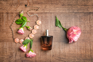 Composition with bottle of perfume and flowers on wooden background