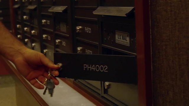 A male's hand is opening US mail box checking new arrivals. Mail is an independent agency responsible for providing postal service in the US.