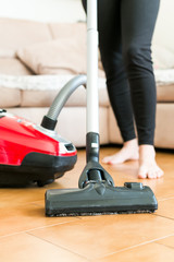 Young woman using a vacuum cleaner in the house.