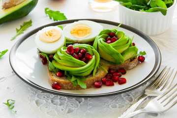Toast with avocado rose, boiled egg and fresh salad on white table cloth