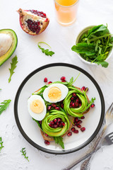 Toast with avocado rose, boiled egg and fresh salad on white table cloth