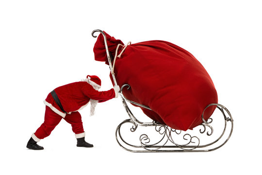 Santa Claus pushing sleigh with huge bag full of christmas gifts isolated on white background