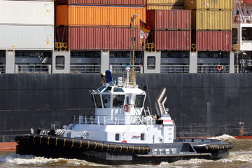 Hafenschlepper vor großem Containerschiff