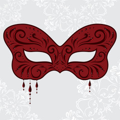 Red masquerade mask in the shape of a butterfly with pendants