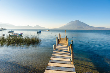 Wooden pier at Lake Atitlan on the shore at Panajachel, Guatemala.  With beautiful landscape scenery of volcanoes Toliman, Atitlan and San Pedro in the background.