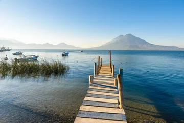 Tuinposter Wooden pier at Lake Atitlan on the shore at Panajachel, Guatemala.  With beautiful landscape scenery of volcanoes Toliman, Atitlan and San Pedro in the background. © Simon Dannhauer