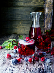 Summer berry lemonade with frozen berries on a wooden rustic table, selective focus