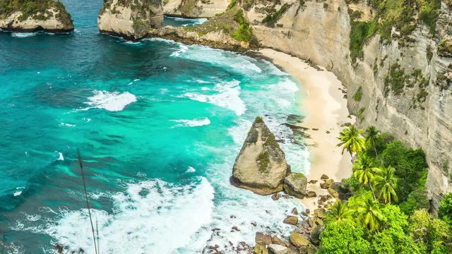 Timelapse Rock in the ocean with beautiful palms behind at Atuh beach on Nusa Penida island, Indonesia