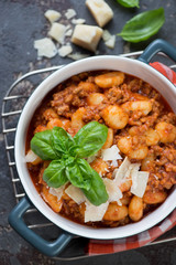 Bowl of potato gnocchi with meat sauce and cheese, above view, vertical shot