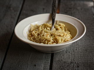 a portion of fast food noodles in a white plate on a wooden table