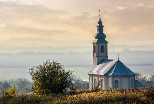church on a hill over the hazy rural valley at sunset. lovely autumn countryside scenery