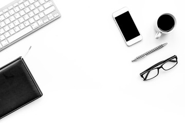 Stylish office desk. Trendy monochrome. Black notebook, glasses, pen, cell phone and  coffeee on white background top view copyspace