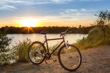 Fahrrad am Ufer eines Sees beim Sonnenuntergang
