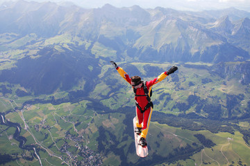 High angle view of skydiver surfing on sky board over mountains