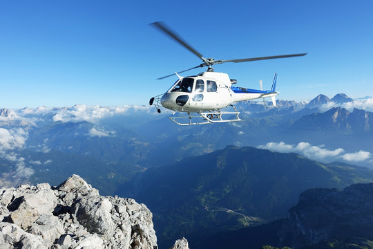 Helicopter approaching BASE jumper exit at the cliff edge
