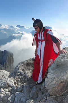 Male wingsuit BASE jumper preparing to fly from cliff edge