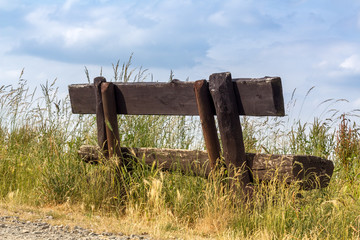 Eine Holzbank im Grünen am Rand eines Wanderweges, Konzept Ruhepause