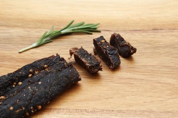 Sliced biltong (protein snack) on a wooden board. This image has selective focusing