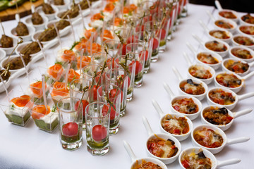 Little glasses with fresh salads stand on white table
