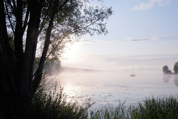 Morning mist over lake with sailboat - 6