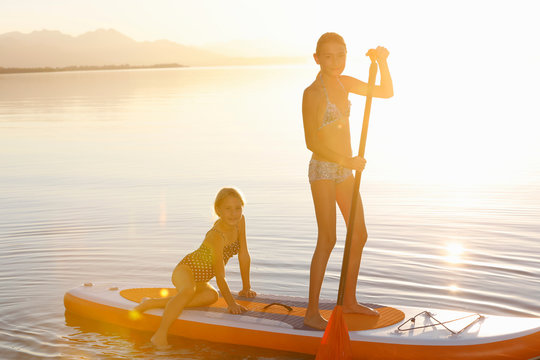 Two young girls paddle boarding on water