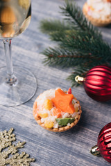 Crab salad tarts on wooden background. Christmas holiday buffet table served by canape snacks. Red baubles, fir-tree branches. Glass of champagne