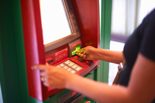Cropped view of woman withdrawing money from cash machine