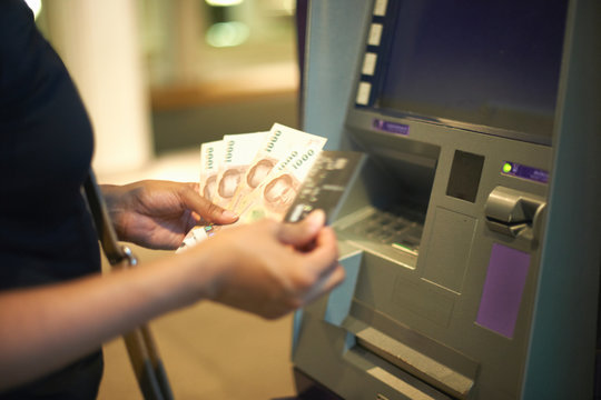 Cropped view of woman withdrawing money from cash machine