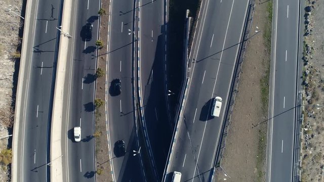 Aerovideo: unmanned aircraft flying over free interstate expressway with machines at spring day. The modern architecture of curvy autoban, many different winding turn. Casual lifestyle in megapolis