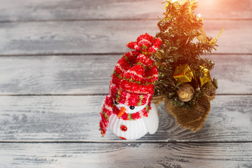 Toy snowman, and Christmas tree on a light wooden background