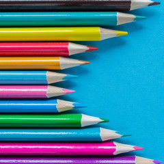 Multicolored pencils on a blue background with a large frame