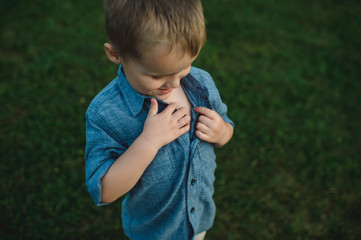Boy unbuttoning shirt to investigate chest